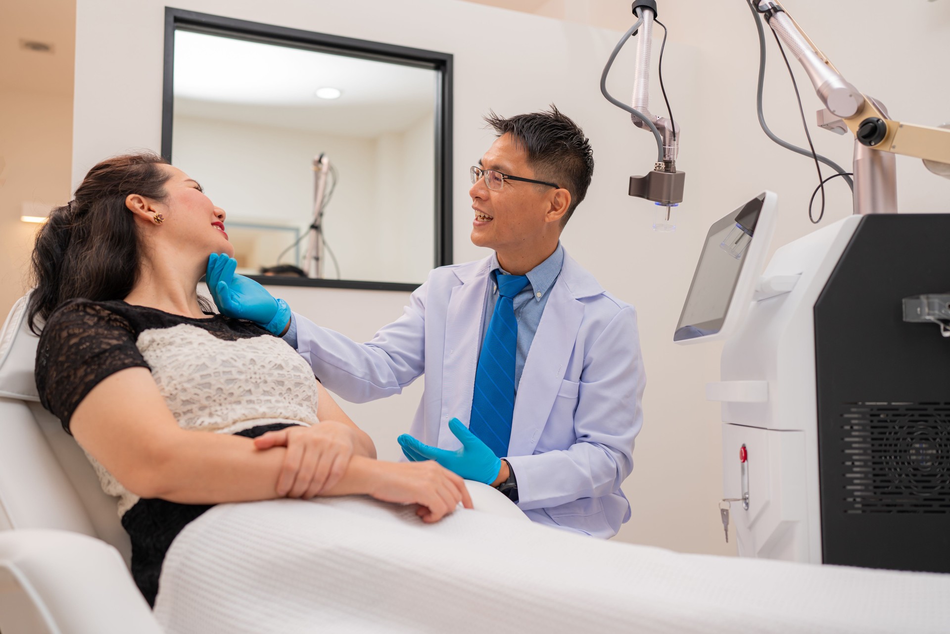 Mature male doctor taking care and talking mature female sleep on bed in beauty clinic.