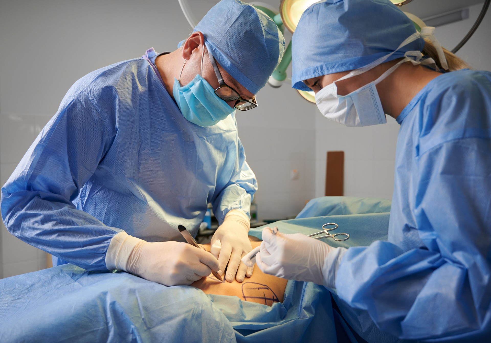 Surgeon and assistant doing plastic surgery in operating room.